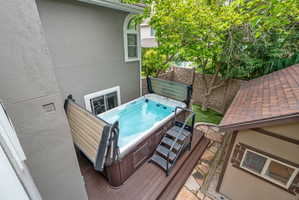 Arctic brand salt water swim spa with dark wood-finish paneling and a hydraulic lift protective cover, set on a Trex deck with stairs