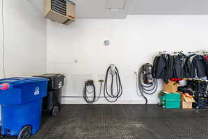 Expansive wall mounted heated garage space with epoxy floors covered with rubber tiles, EV charging station and wall vacuum