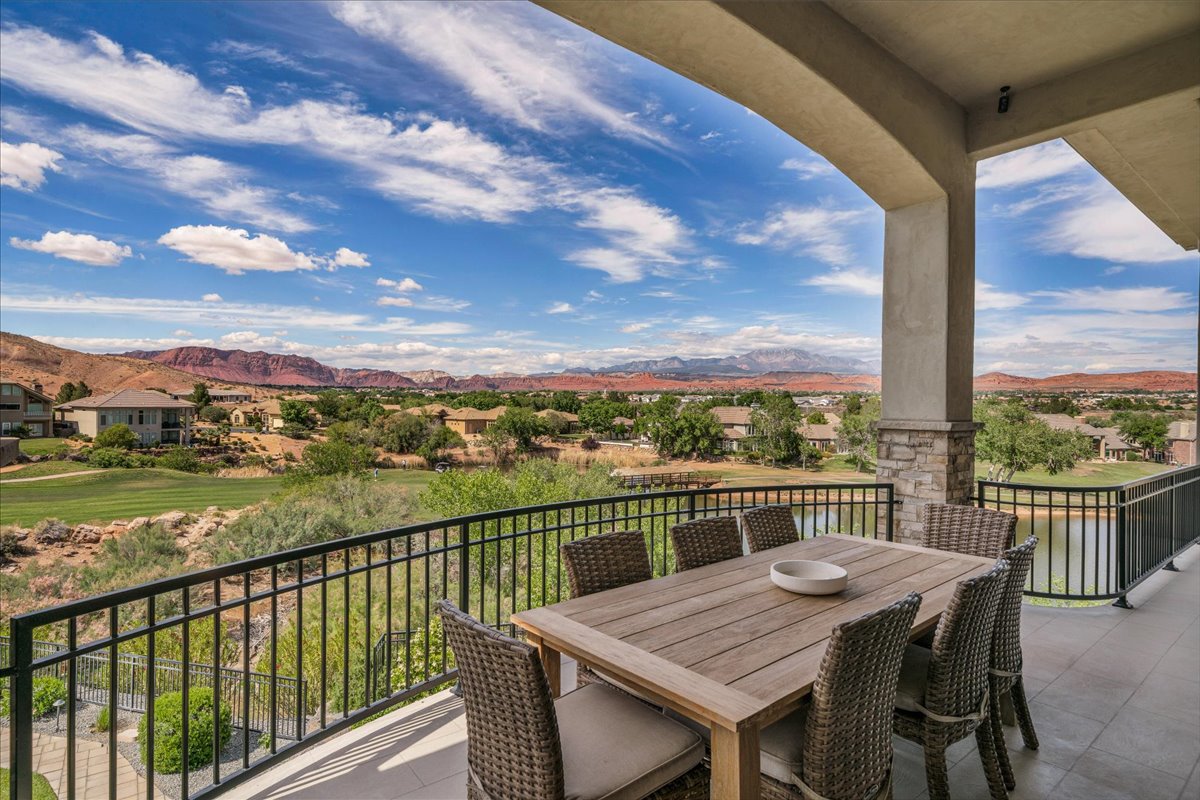 Expansive covered deck featuring a stone-clad column, black wrought iron railing, and tiled flooring