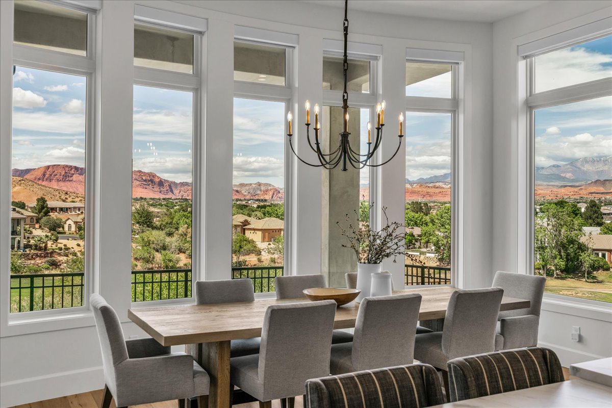 Spacious dining area featuring expansive windows, a prominent chandelier, and wood-finish flooring