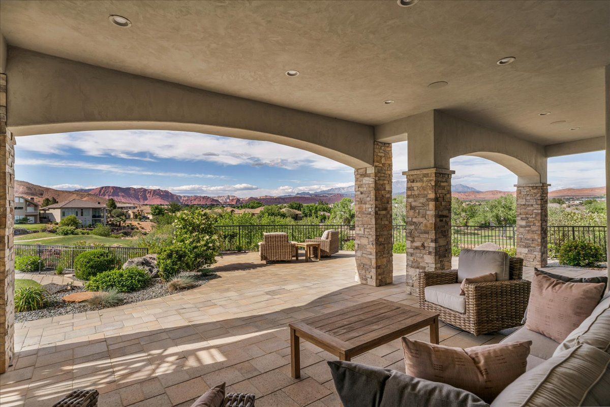 Expansive covered patio featuring stone-clad pillars, arched openings, recessed lighting, and a paver stone surface