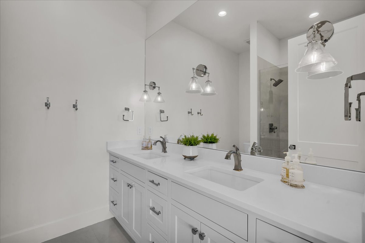 Bathroom featuring a dual vanity with white shaker-style cabinetry, a solid surface countertop, and undermount sinks