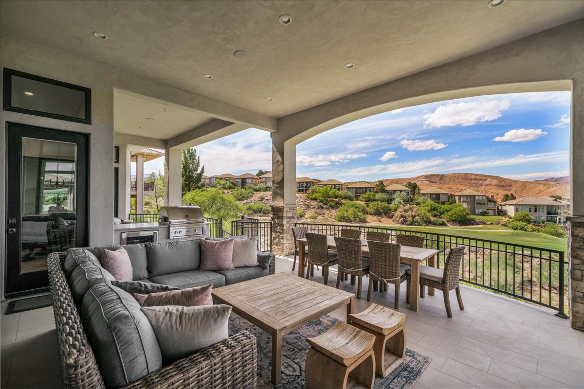 Expansive covered patio featuring a built-in outdoor kitchen with stainless steel appliances, recessed lighting, and tile flooring