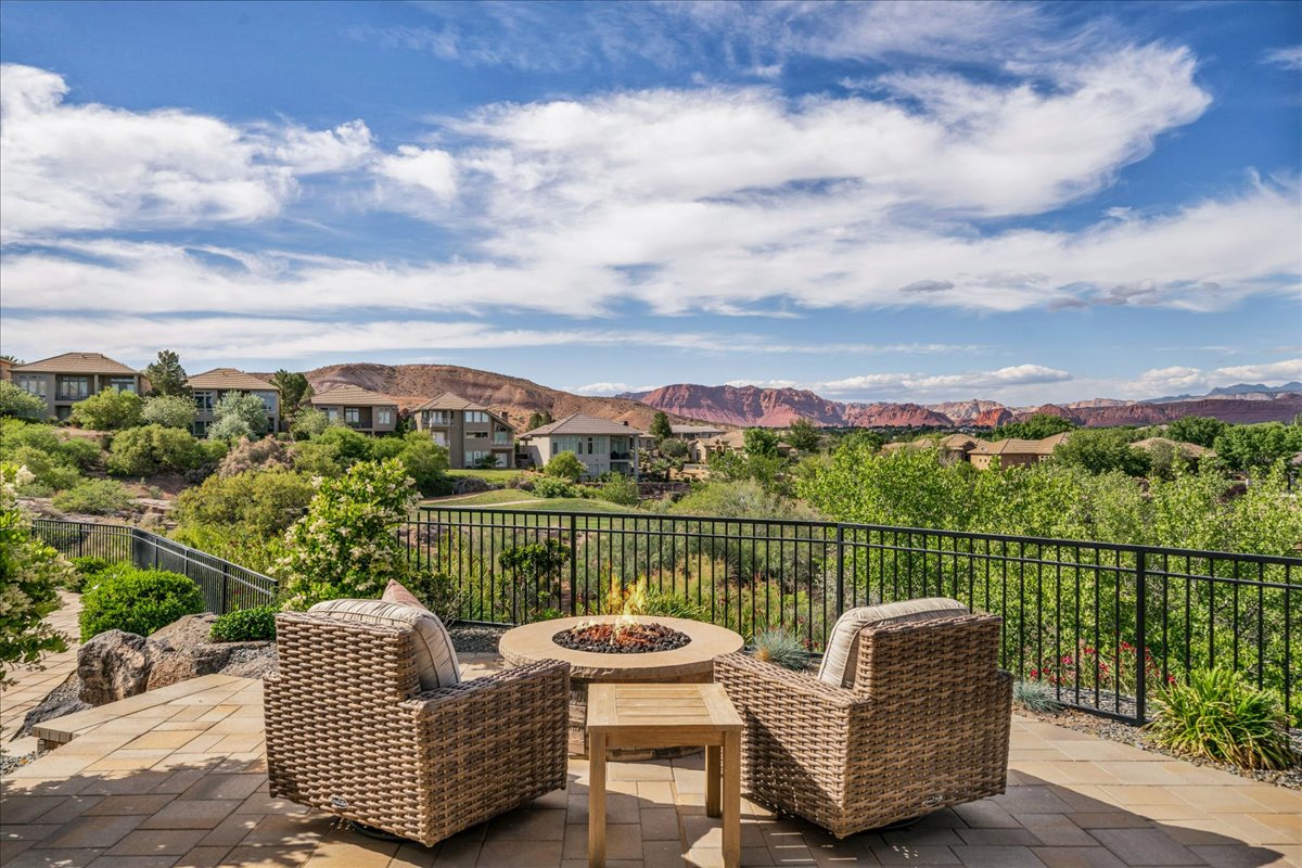 Expansive outdoor patio featuring a paver stone surface, a built-in fire pit, and a black metal railing