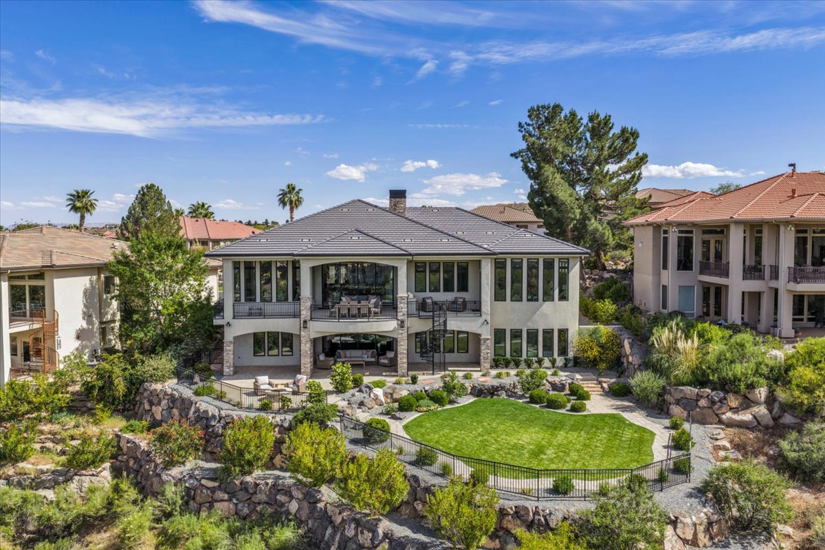 Exterior featuring a multi-level design with a dark shingle roof and a stucco finish