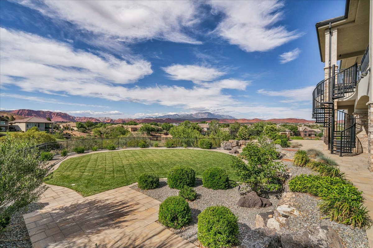 Expansive backyard featuring a manicured lawn, paver patio, and low-maintenance landscaping