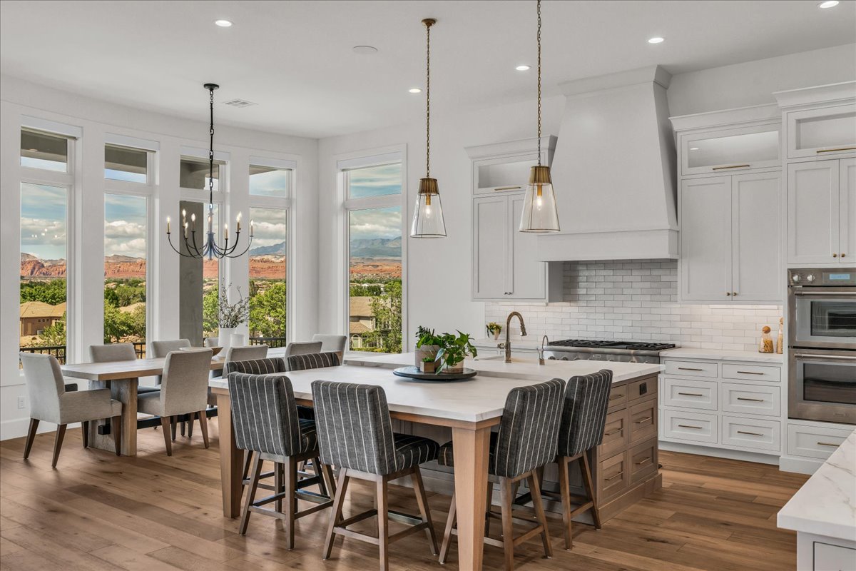 Open-concept kitchen and dining area featuring a large center island with seating, extensive white cabinetry, professional-grade appliances, and wood-finish flooring