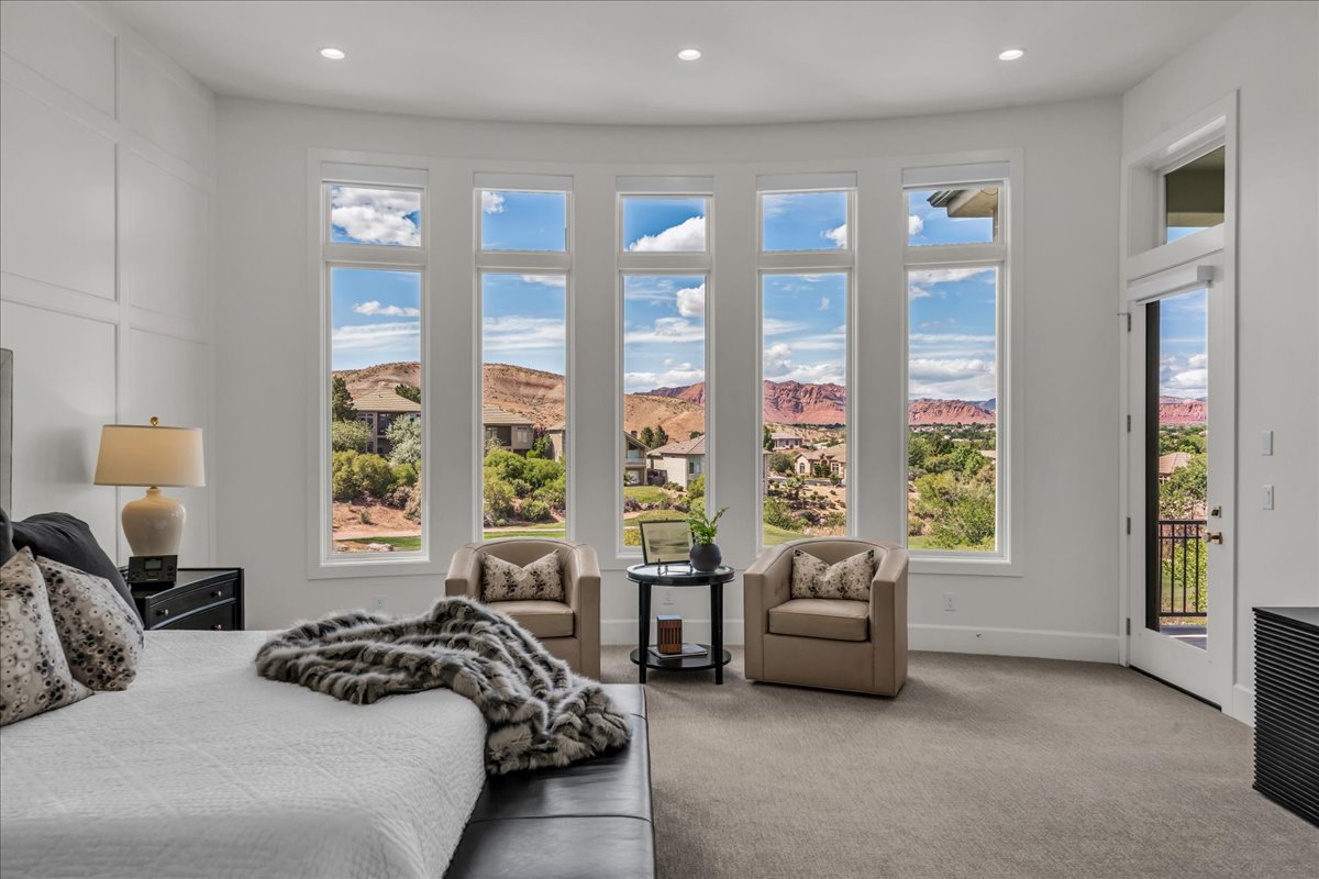 Primary bedroom: expansive curved window wall presenting distant red rock formations and verdant landscapes