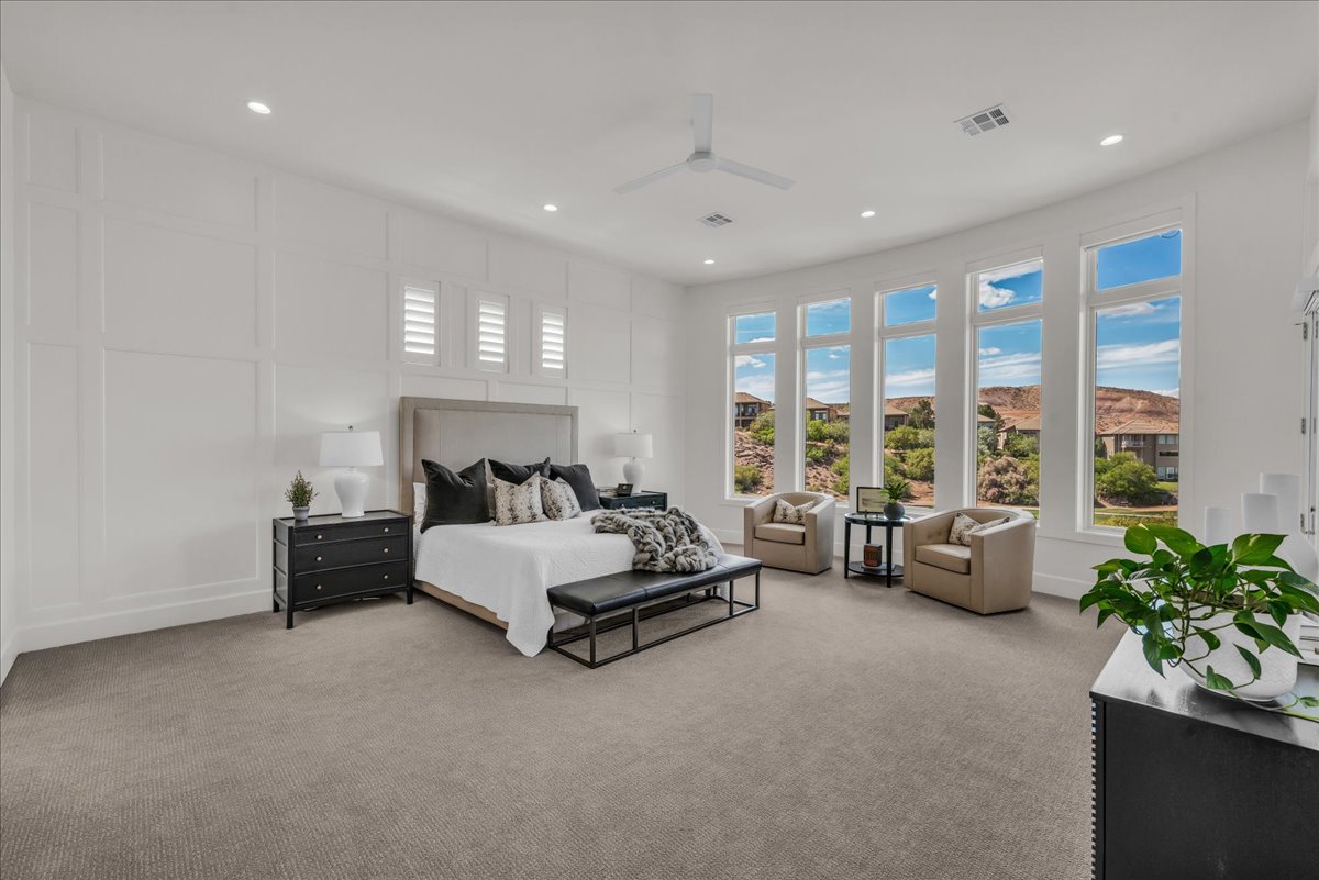 Primary bedroom featuring five tall windows with white framing, recessed lighting, and a white ceiling fan
