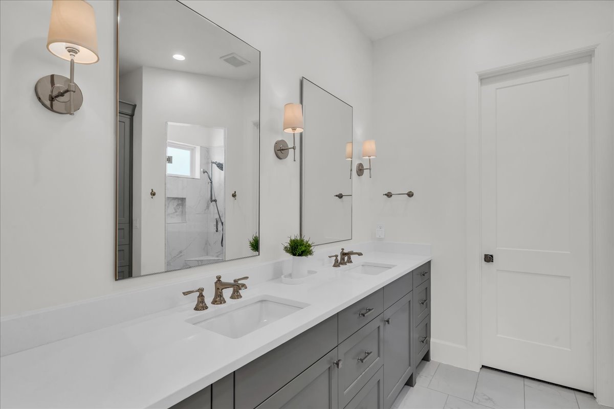 Dual vanity with gray cabinetry, white countertops, and brushed nickel fixtures