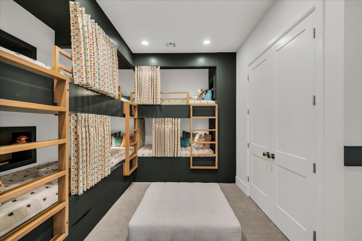 Built-in bunk beds with individual privacy curtains, recessed lighting, and a soft carpeted floor