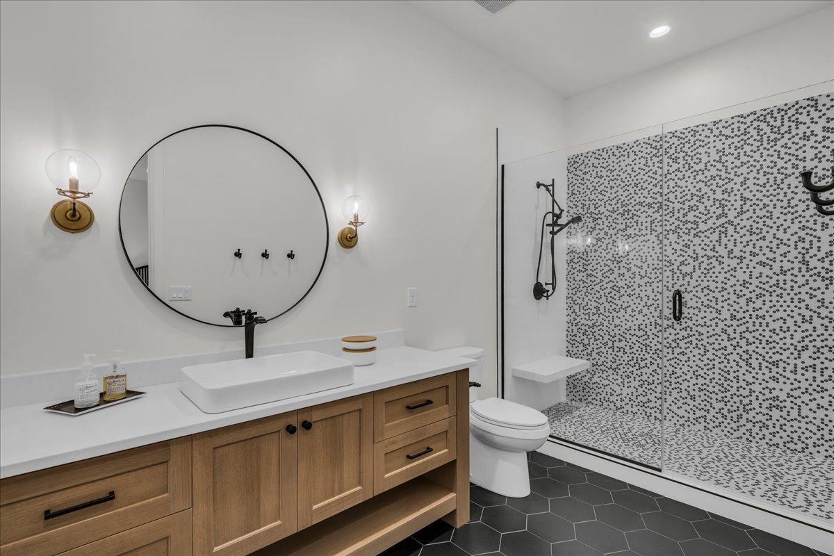 Bathroom featuring a wood-finish vanity with quartz countertop, vessel sink, and matte black fixtures