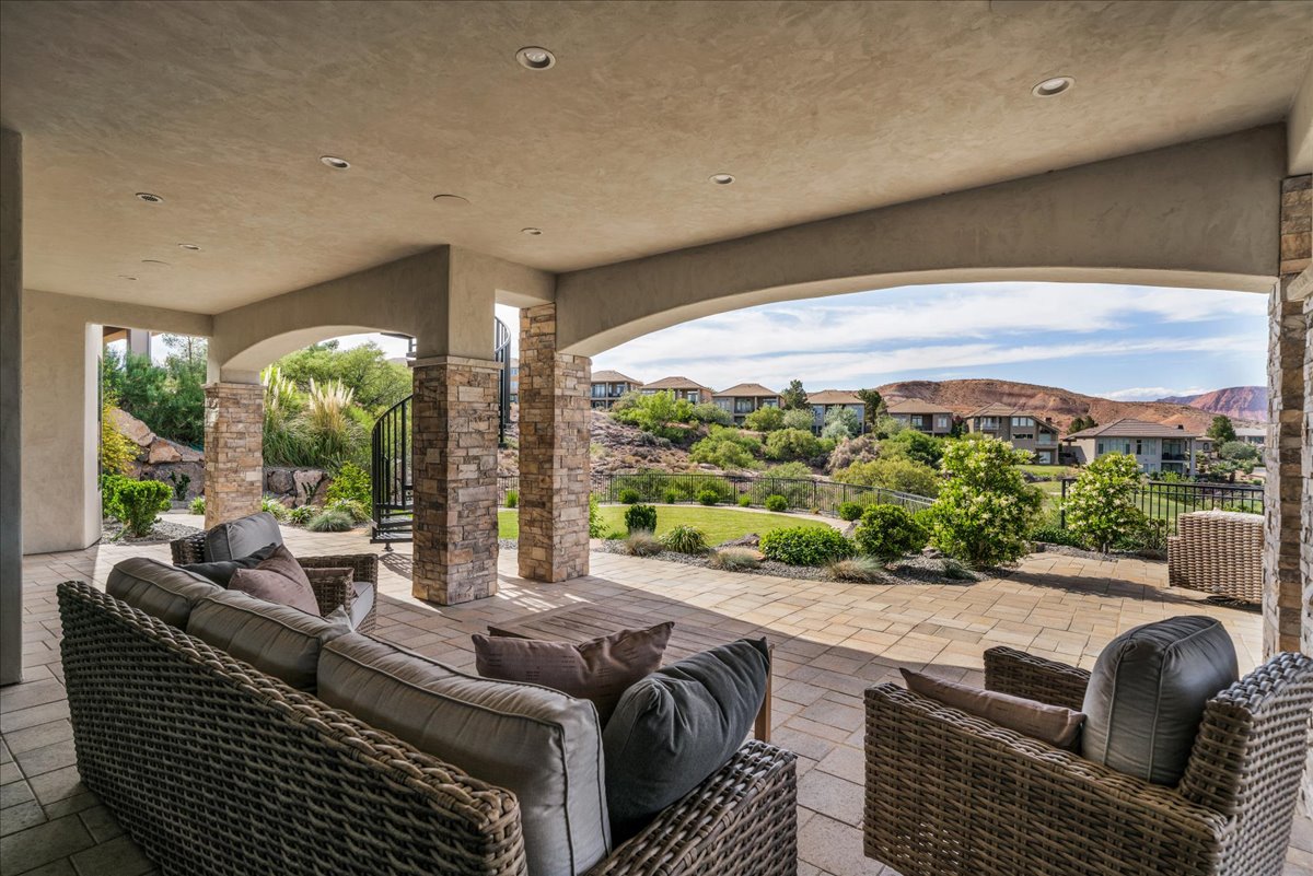 Expansive covered patio featuring stone-clad columns, arched openings, recessed lighting, and a paved surface