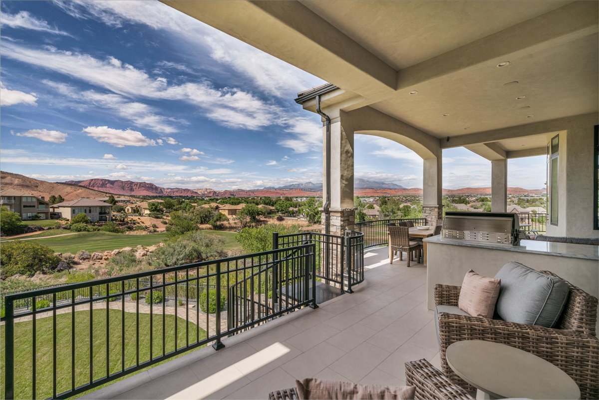 Spacious outdoor patio featuring stone columns, arched openings, a built-in outdoor grill, and a tile floor