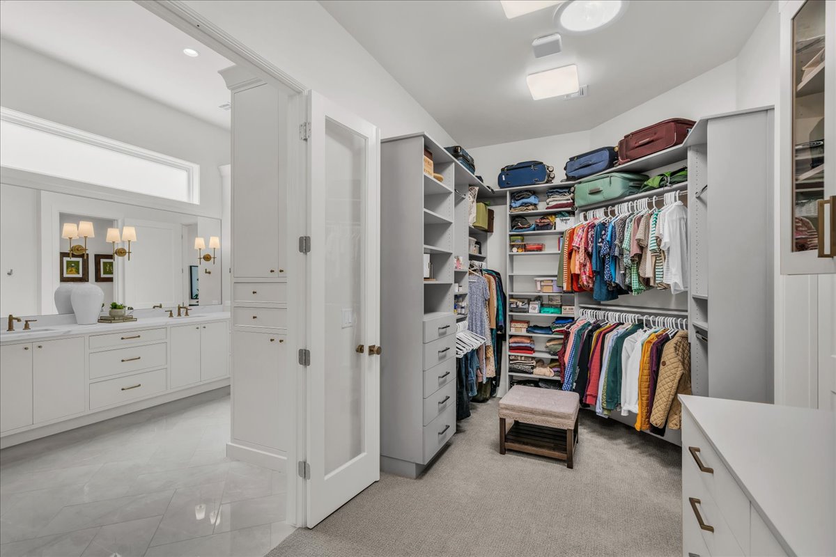 Primary closet featuring abundant shelving, multiple hanging rods, built-in drawers, and carpet flooring