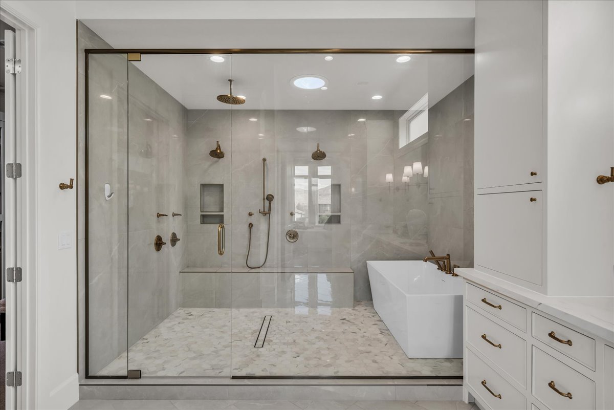 Primary bathroom: walk-in shower with full glass enclosure, dual shower heads, and built-in bench