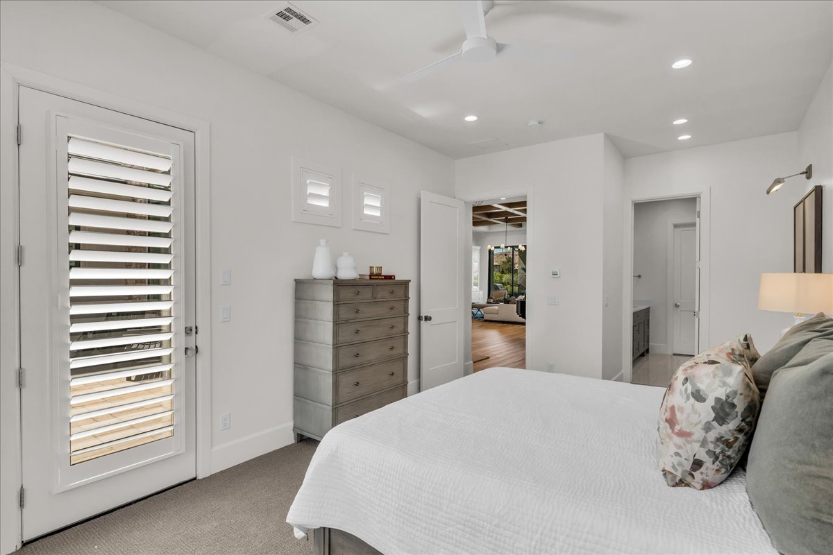 Bedroom featuring a white door with louvered panels, light gray carpeting, recessed ceiling lighting, and a ceiling fan