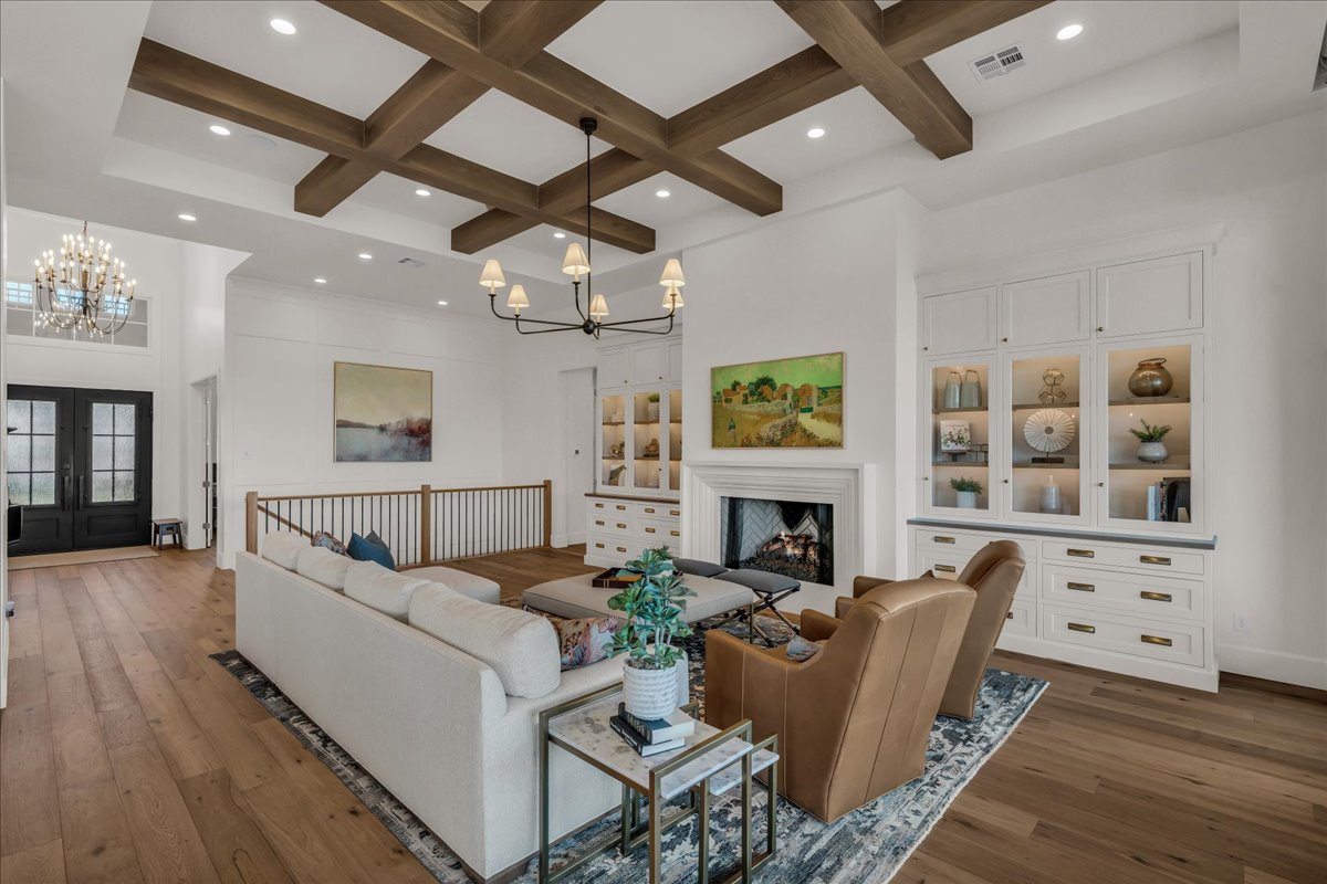 Living space featuring wood-finish flooring, a coffered ceiling with recessed lighting, and a chandelier
