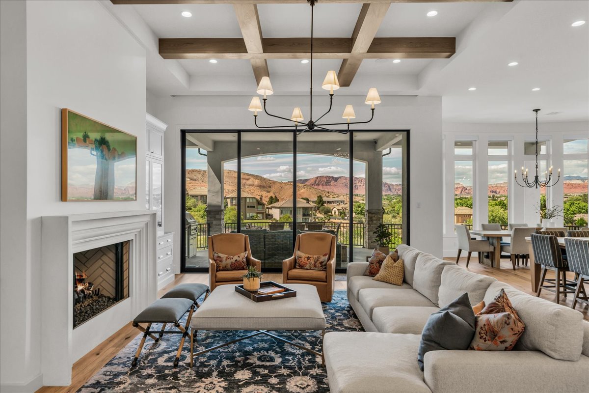 Spacious great room featuring a coffered ceiling with wood beams, a fireplace with a herringbone-patterned firebox, and large glass sliding doors