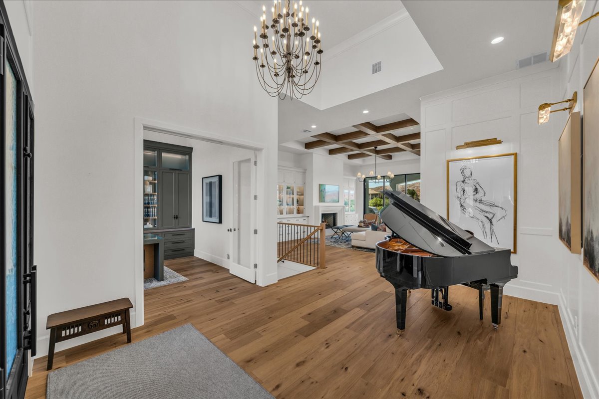 Grand entryway featuring wood-finish flooring, a contemporary chandelier, and wainscoting detailing