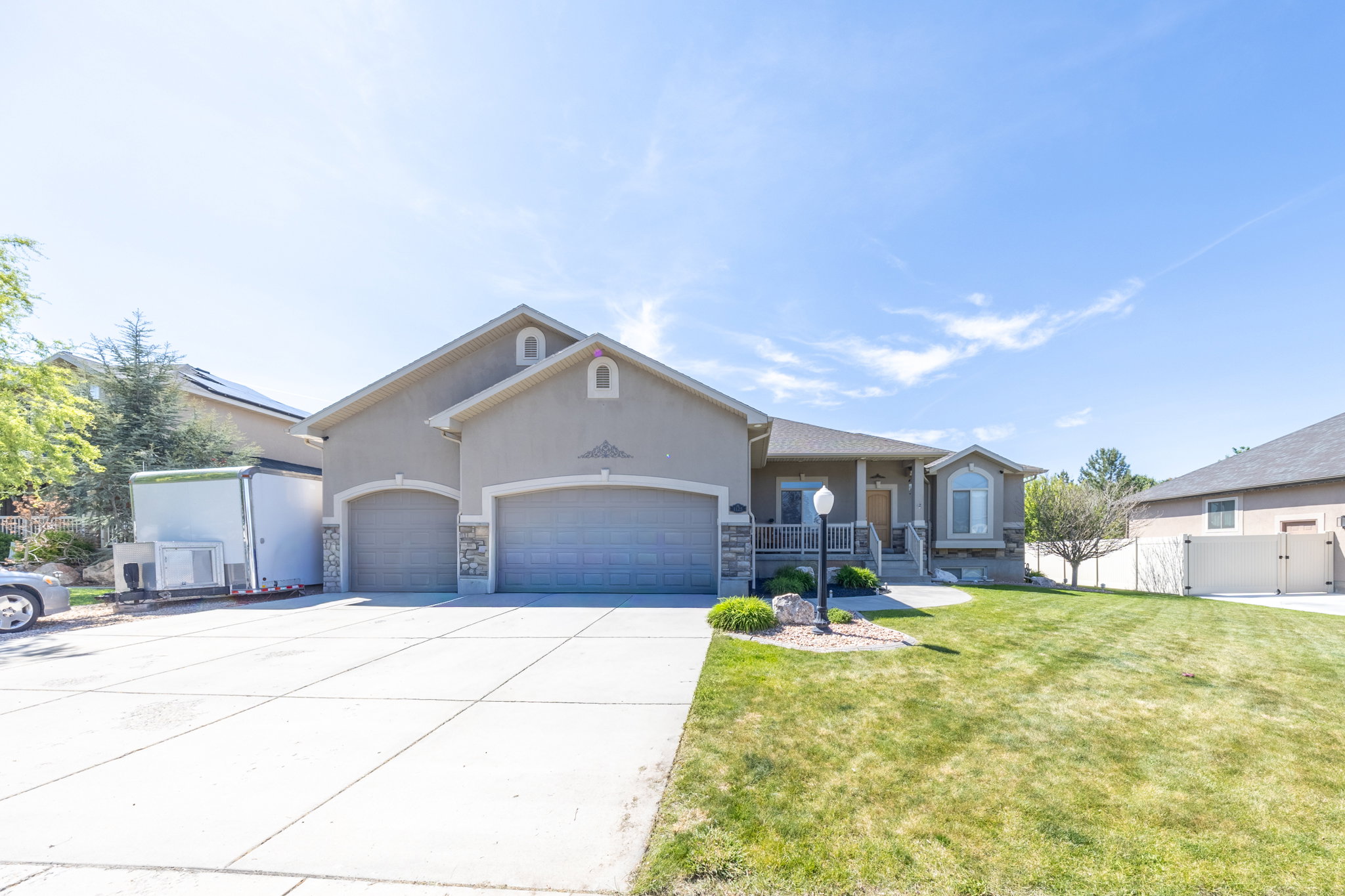 Stucco exterior featuring a large 3 car extra deep garage, covered porch entry, bay window, RV pad and manicured front lawn