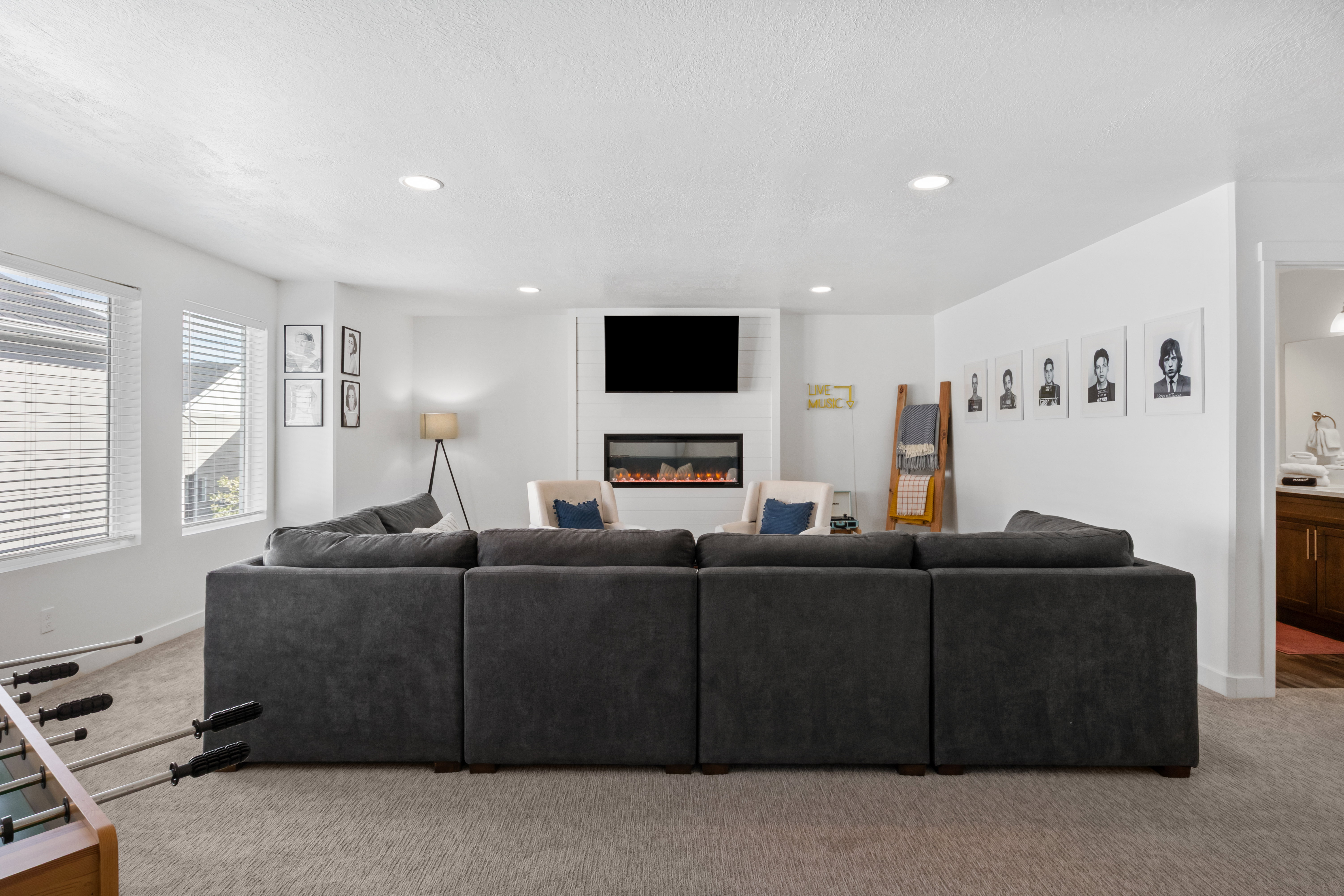 Spacious entertainment room featuring recessed lighting, plush carpeting, an integrated electric fireplace, and multiple windows