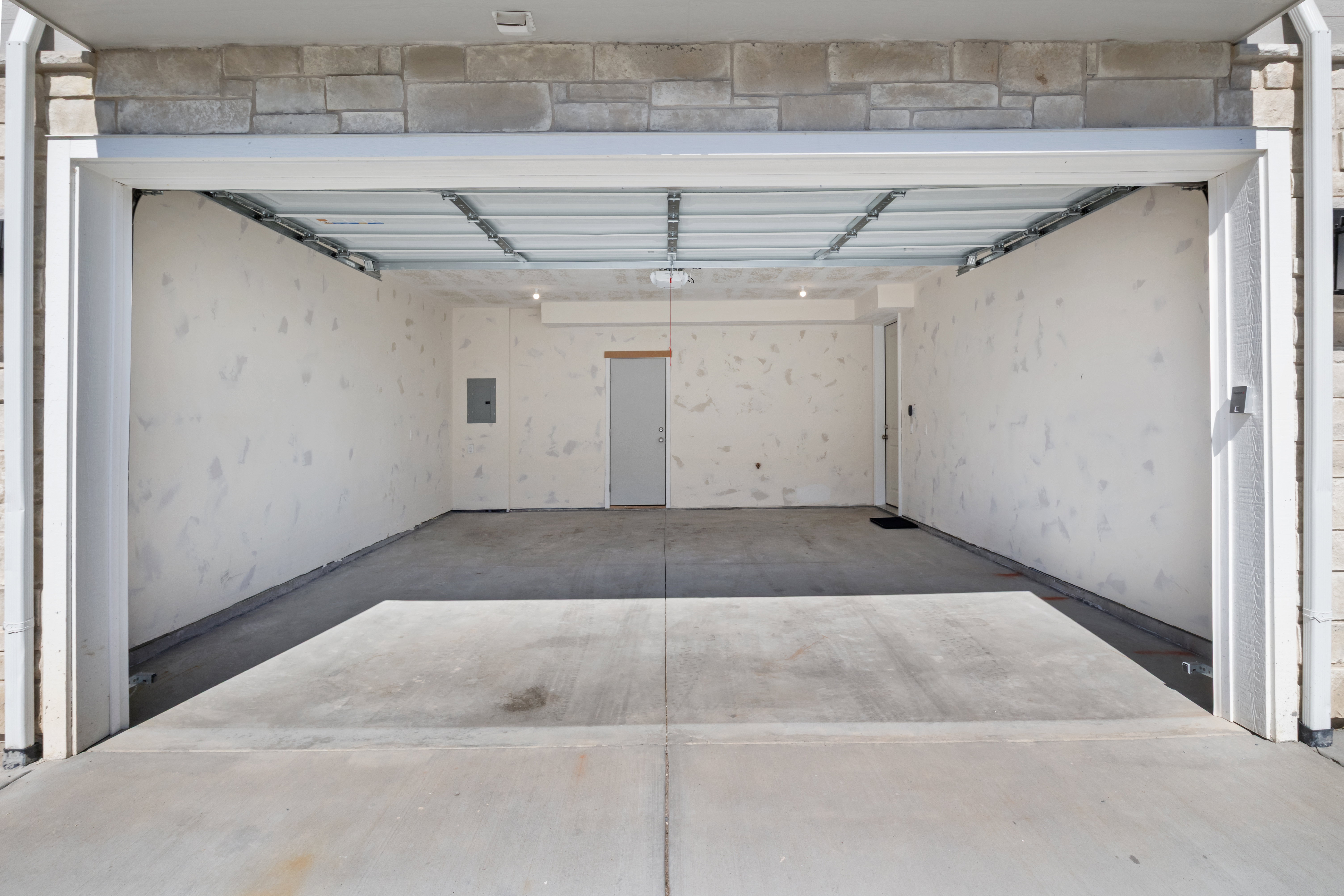 Two-car garage with concrete flooring and exposed ceiling beams