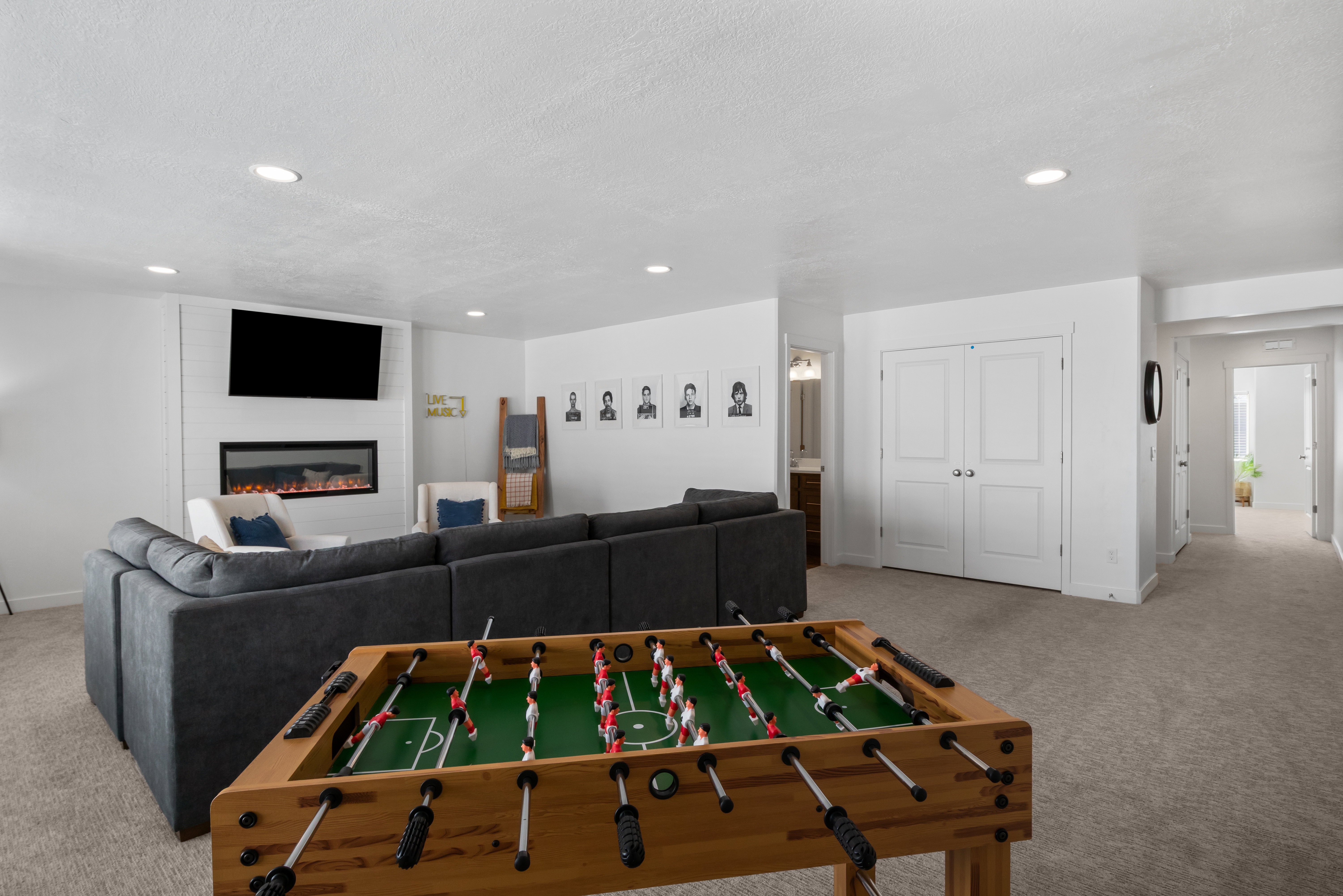 Spacious recreational area featuring recessed lighting, plush carpeting, a contemporary electric fireplace with shiplap-style surround, and double panel interior doors