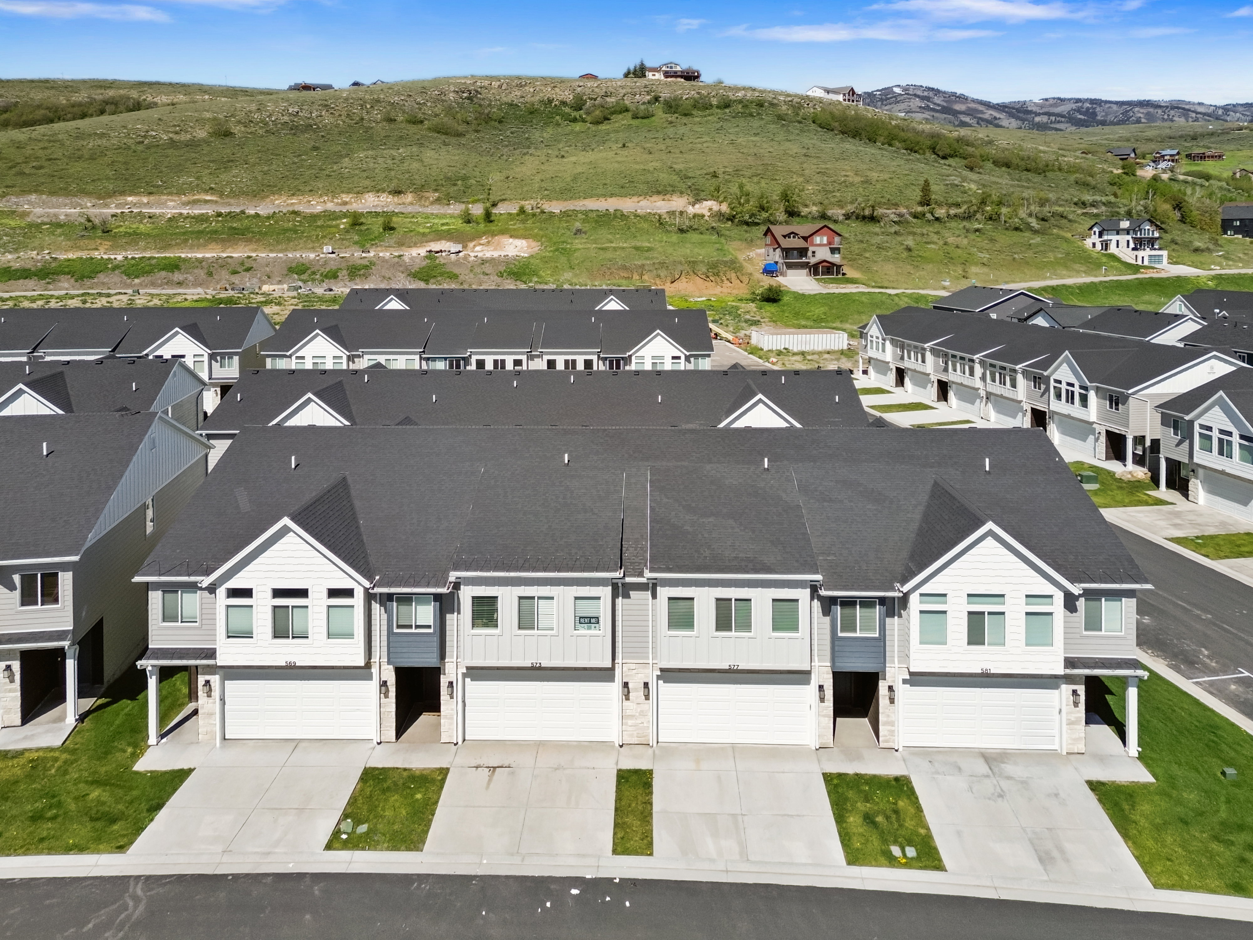 Contemporary townhome with a dark shingle roof, light siding, and an attached two-car garage