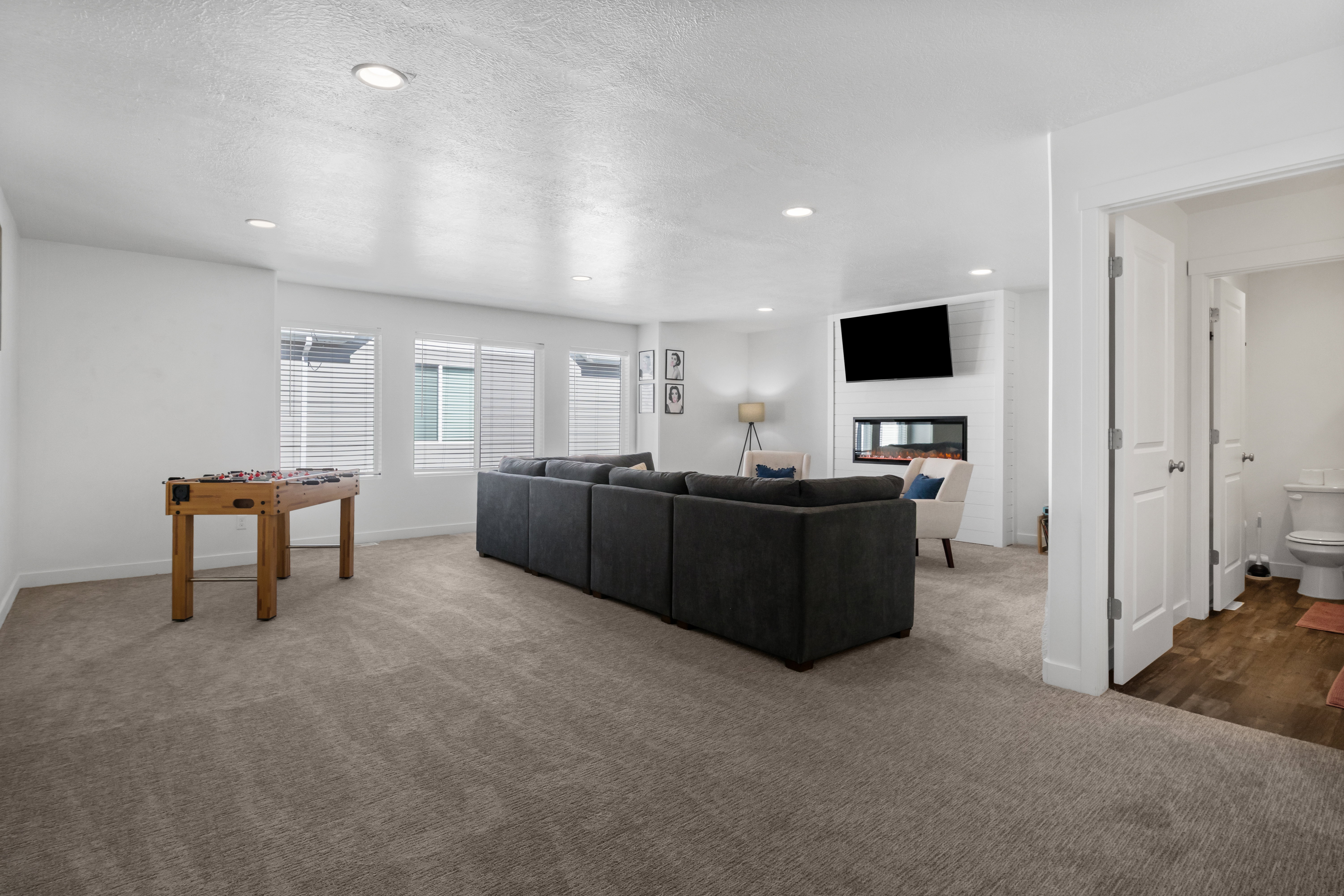Spacious living area featuring recessed lighting, multiple windows with blinds, and a built-in fireplace with a television mount