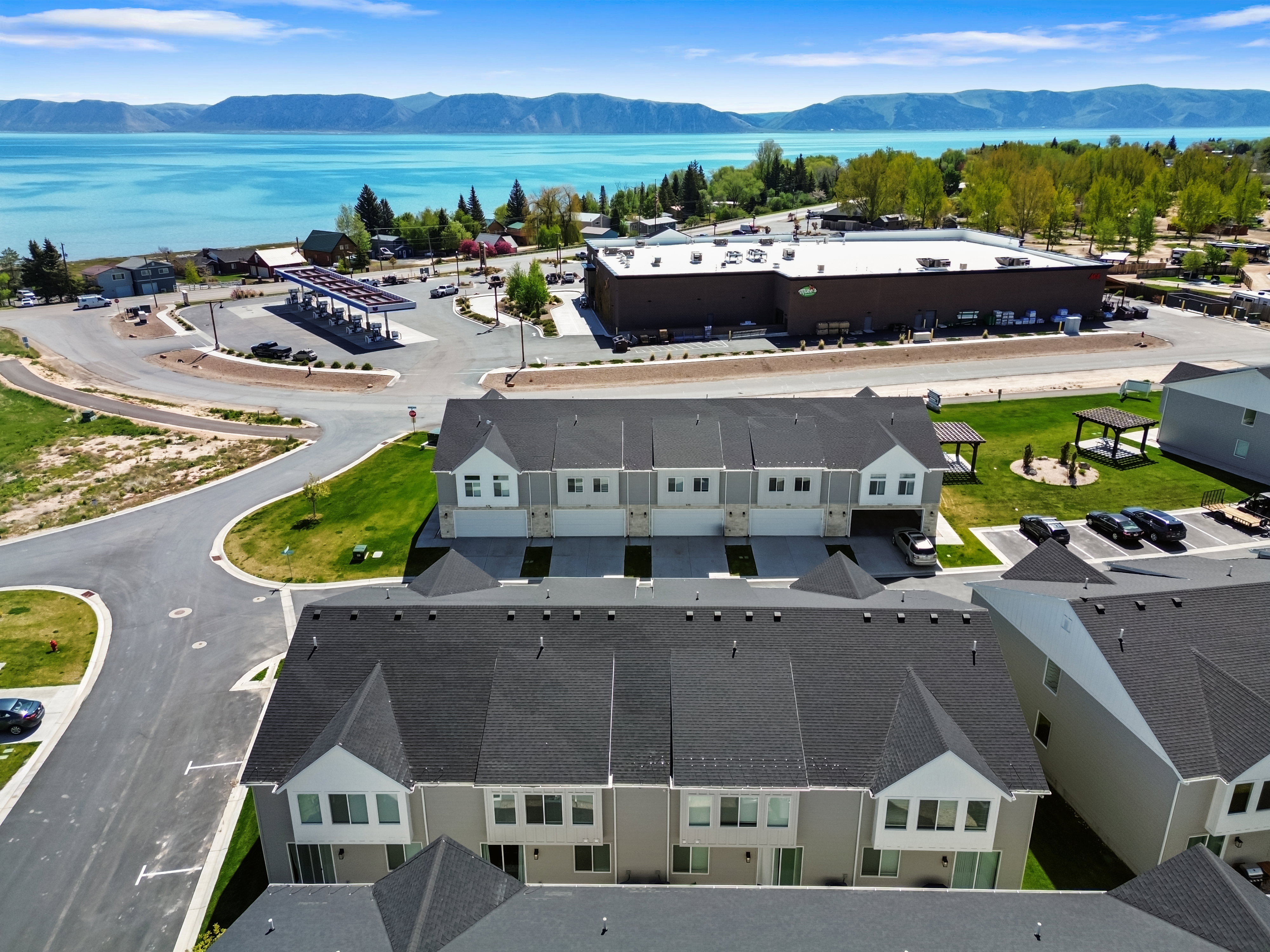 Modern townhome-style residences featuring light-toned siding, dark roofing, and attached garages