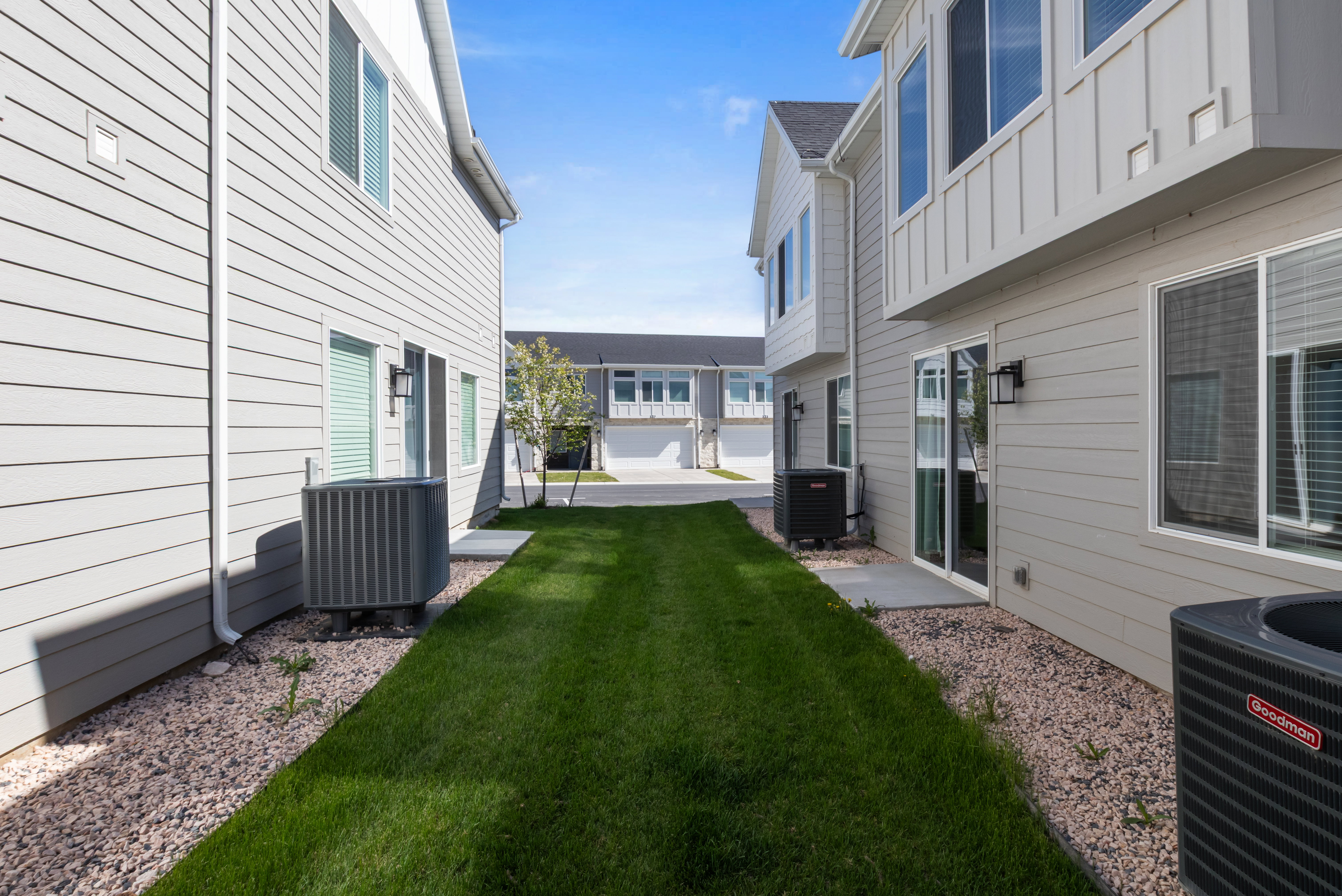 Rear exterior showcasing light gray horizontal siding, white trim, and multiple large windows