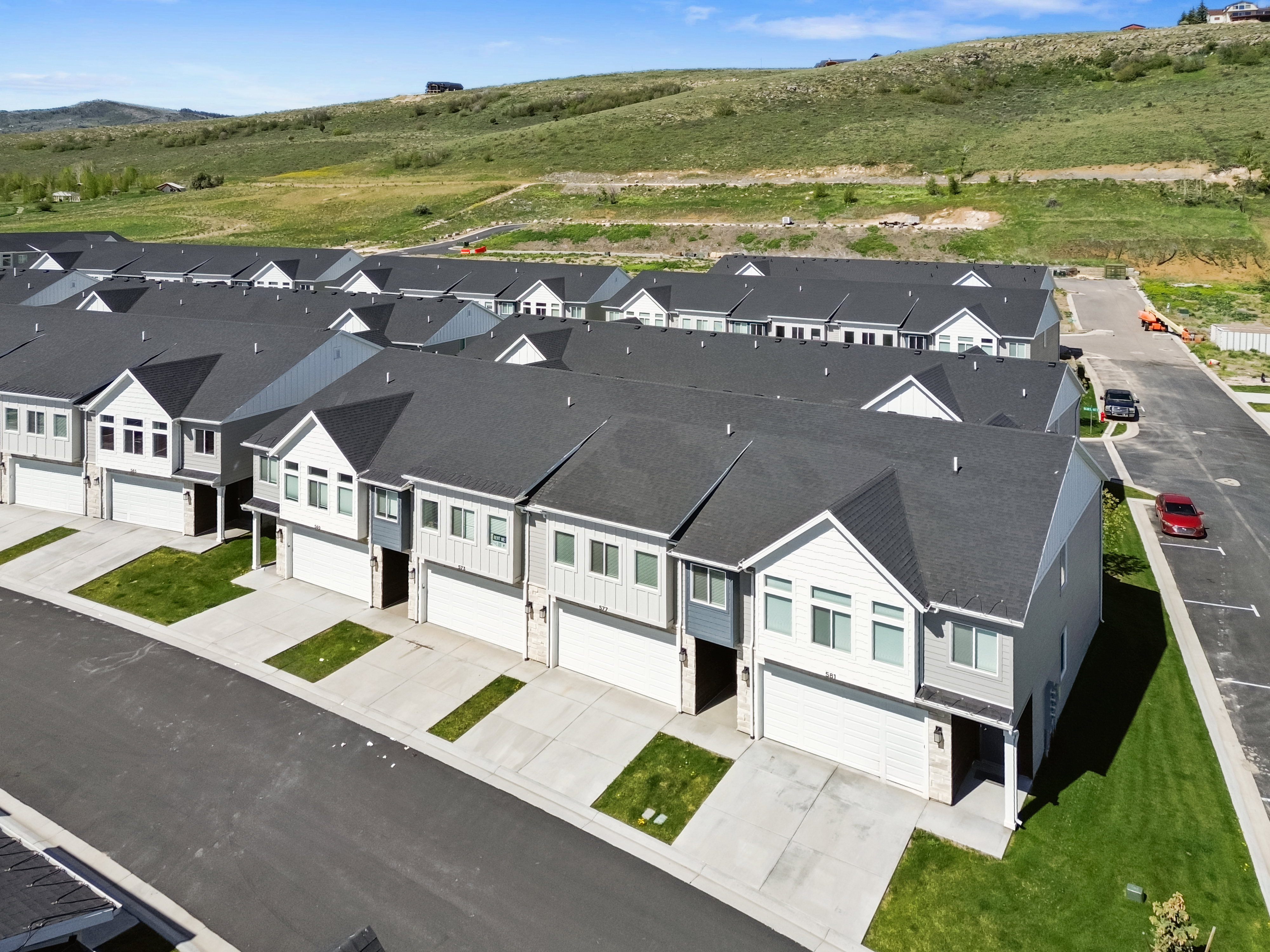 Contemporary townhomes featuring dark shingle roofs and light-toned siding