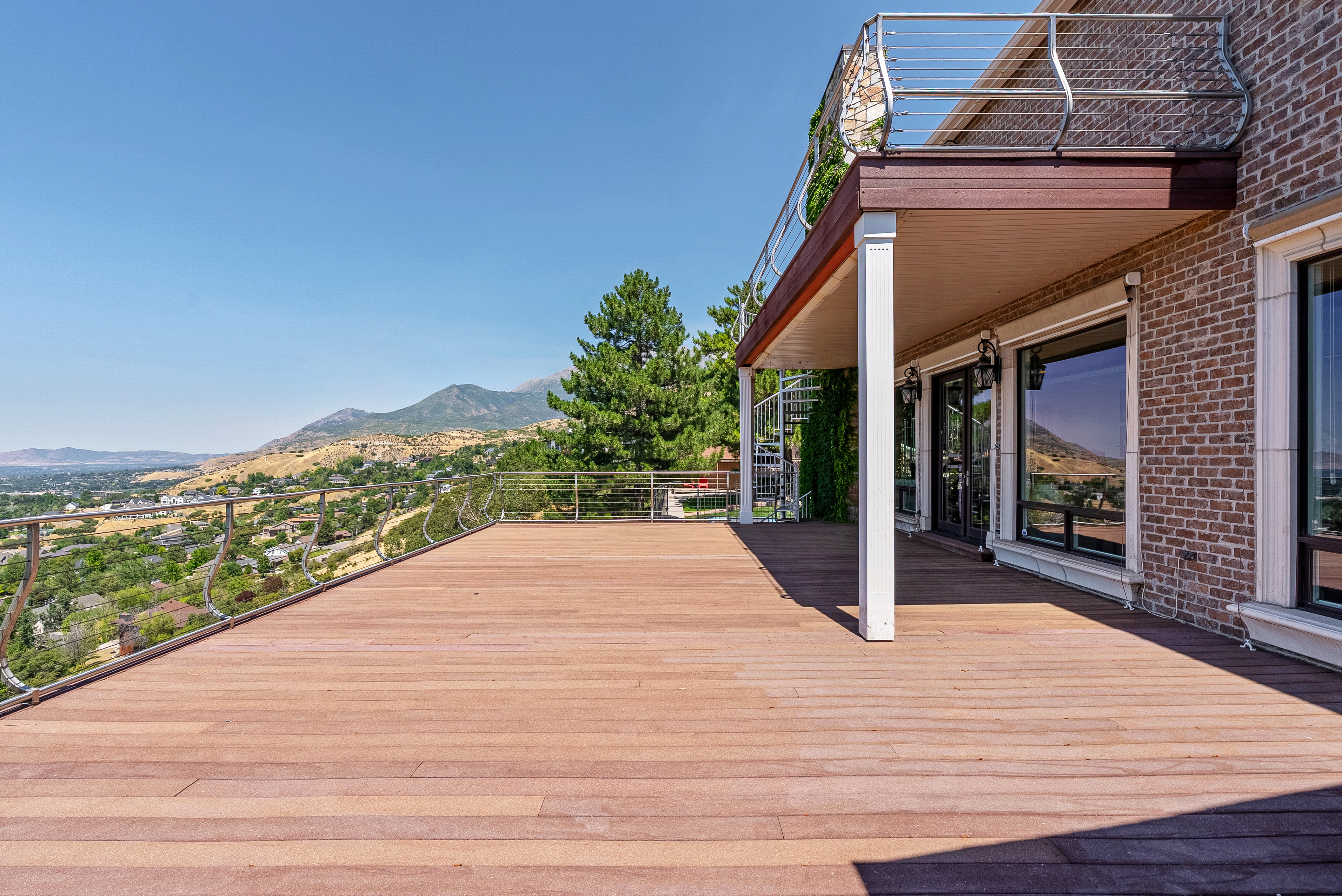 Spacious outdoor deck featuring wood-finish flooring, cable railing, and a spiral staircase