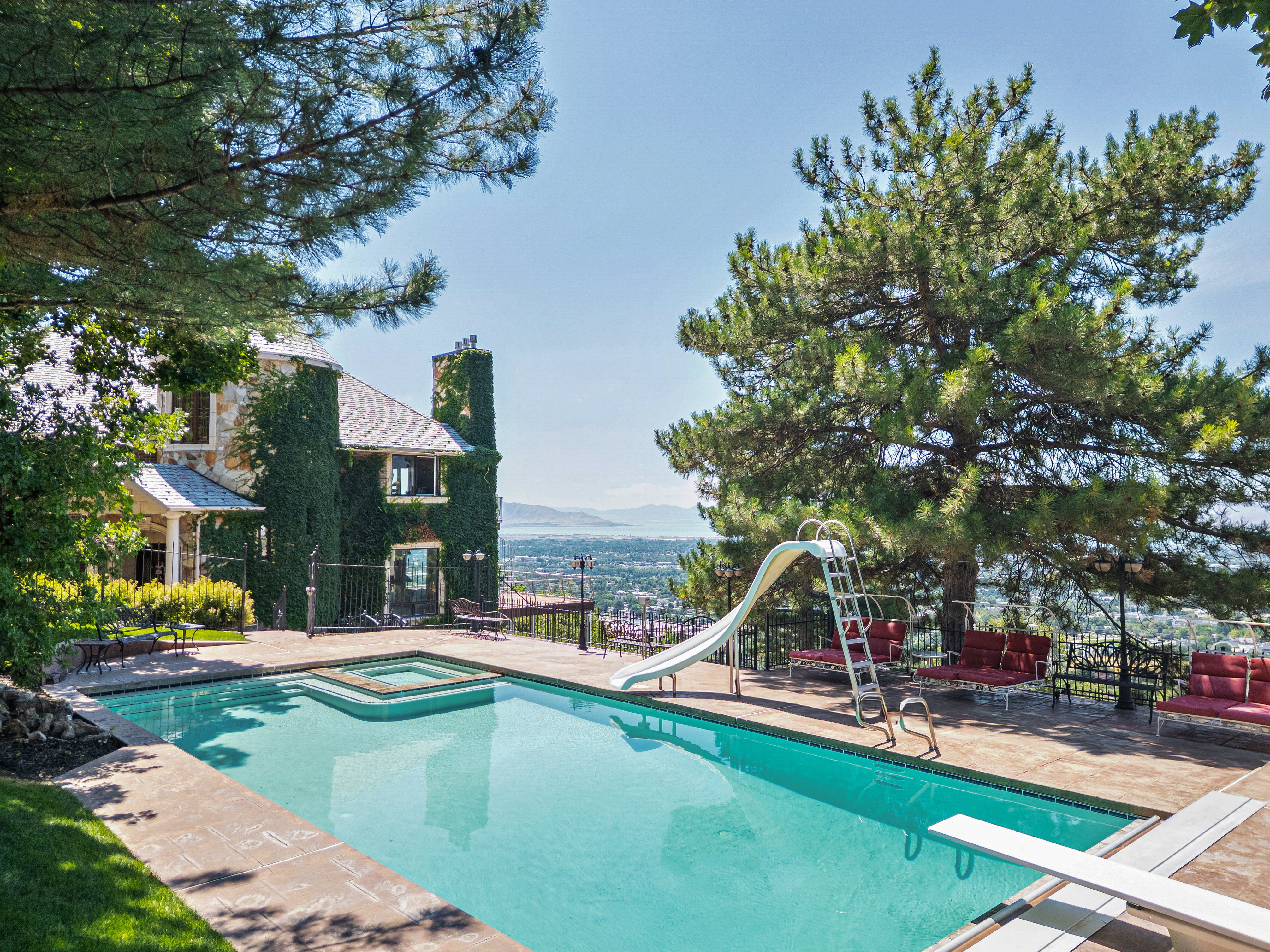 Outdoor swimming pool featuring an integrated spa, diving board, and a water slide