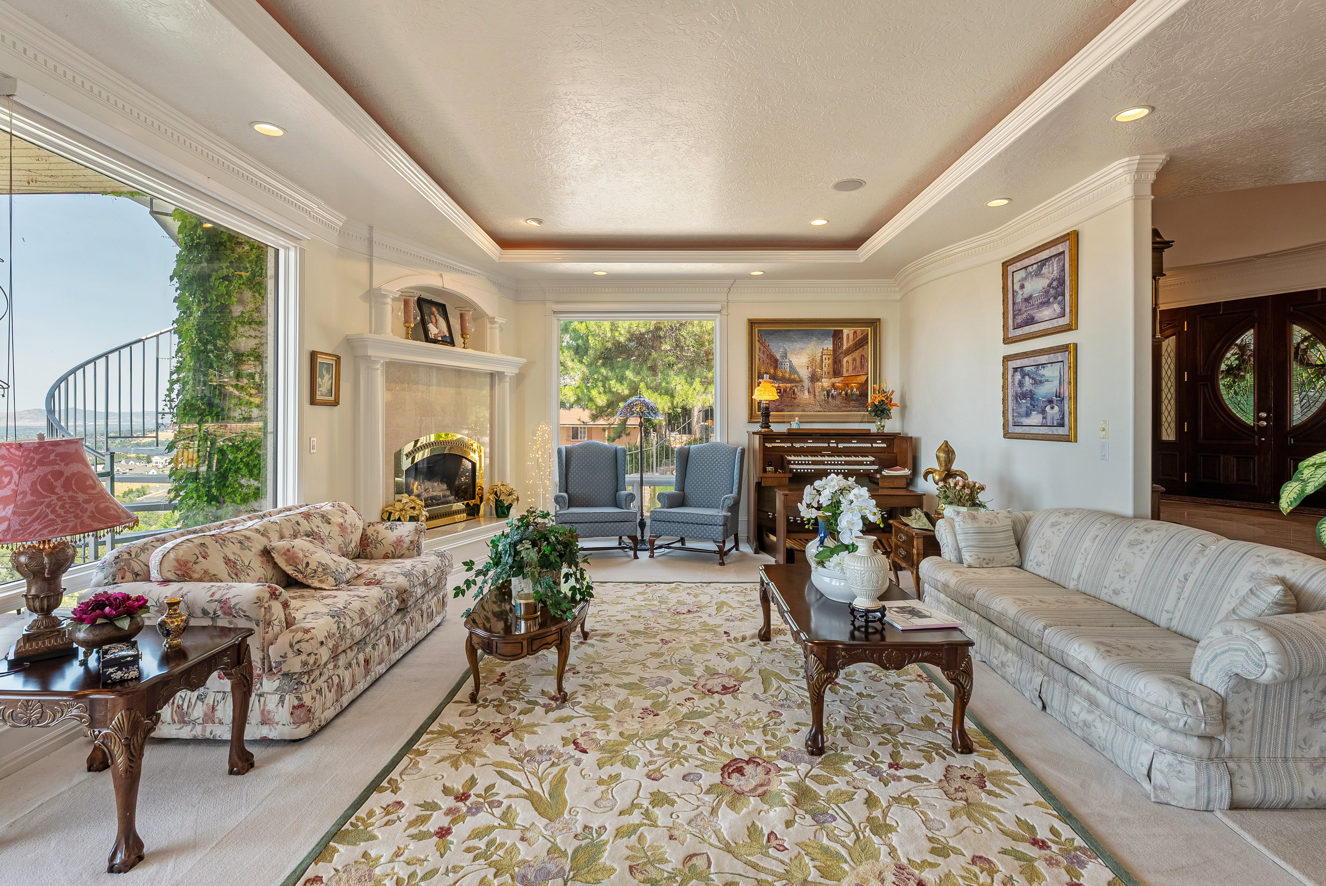 Living area featuring a grand fireplace with an ornate mantel, a large picture window, and recessed lighting