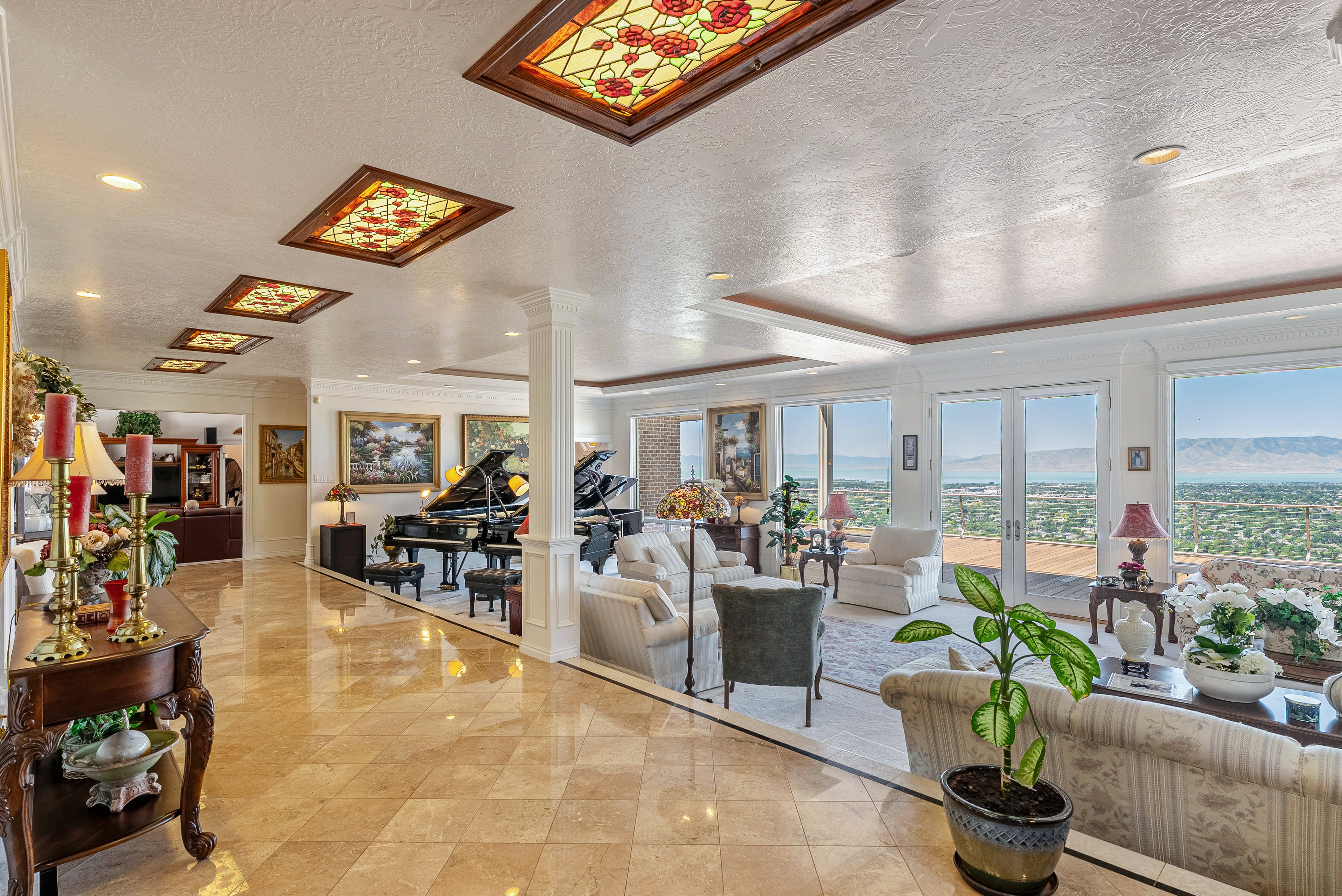 Expansive formal living area featuring checkerboard tile flooring, recessed lighting, and multiple stained-glass ceiling panels