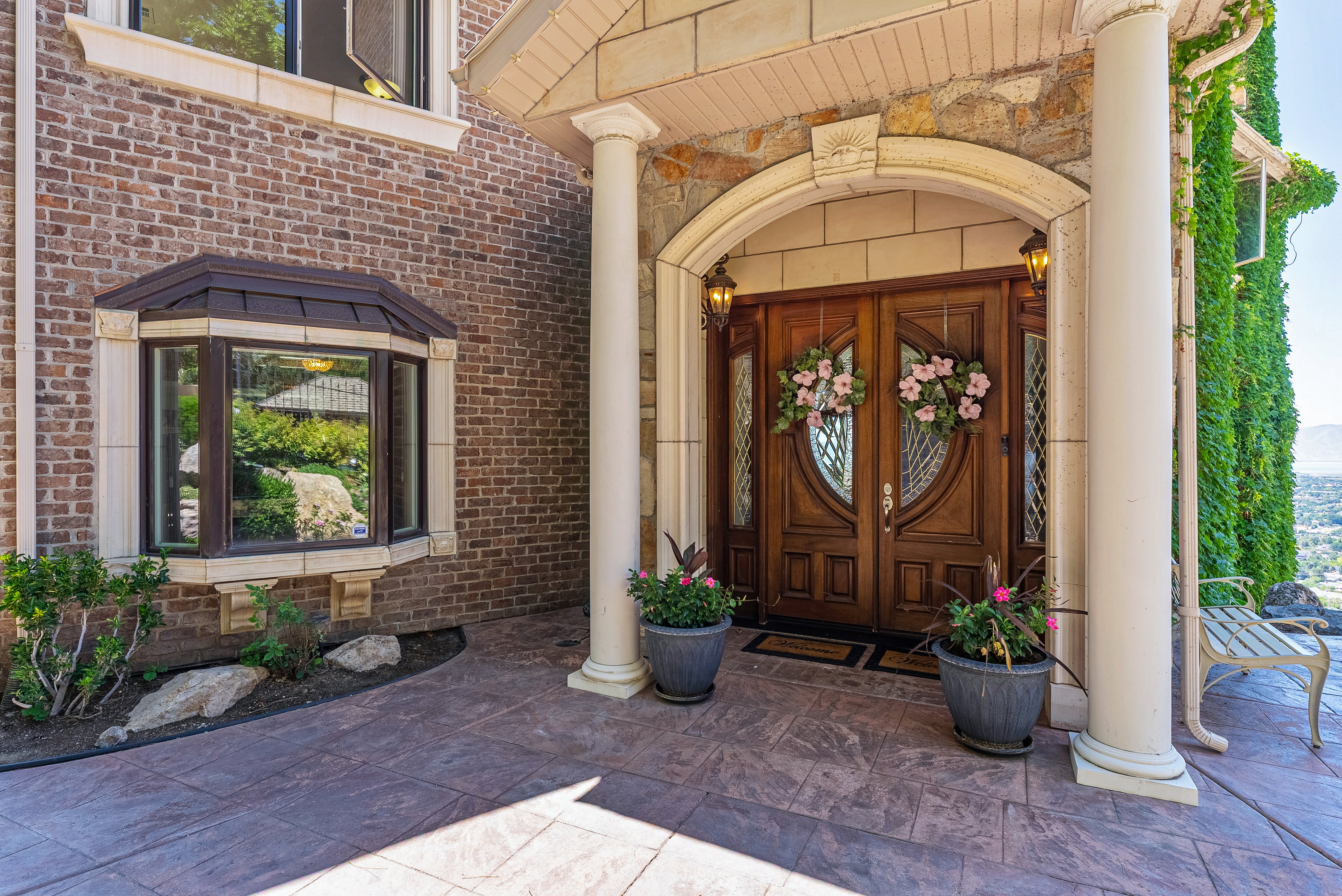 Elegant double front doors with decorative glass panels and an arched stone surround