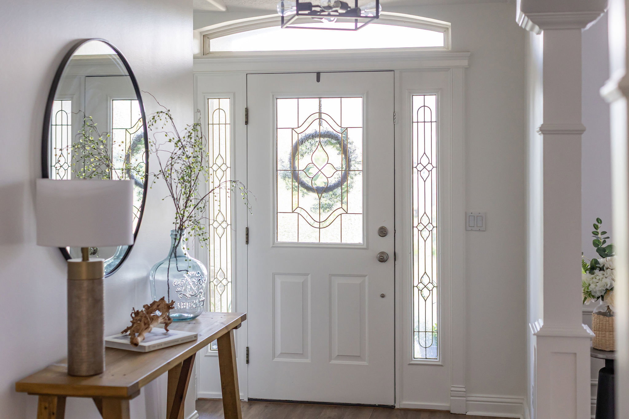 Entryway featuring a white paneled door with decorative glass inserts, matching sidelights, and an arched transom window
