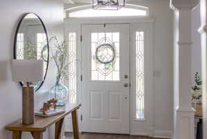 Entryway featuring a white paneled door with decorative glass inserts, matching sidelights, and an arched transom window