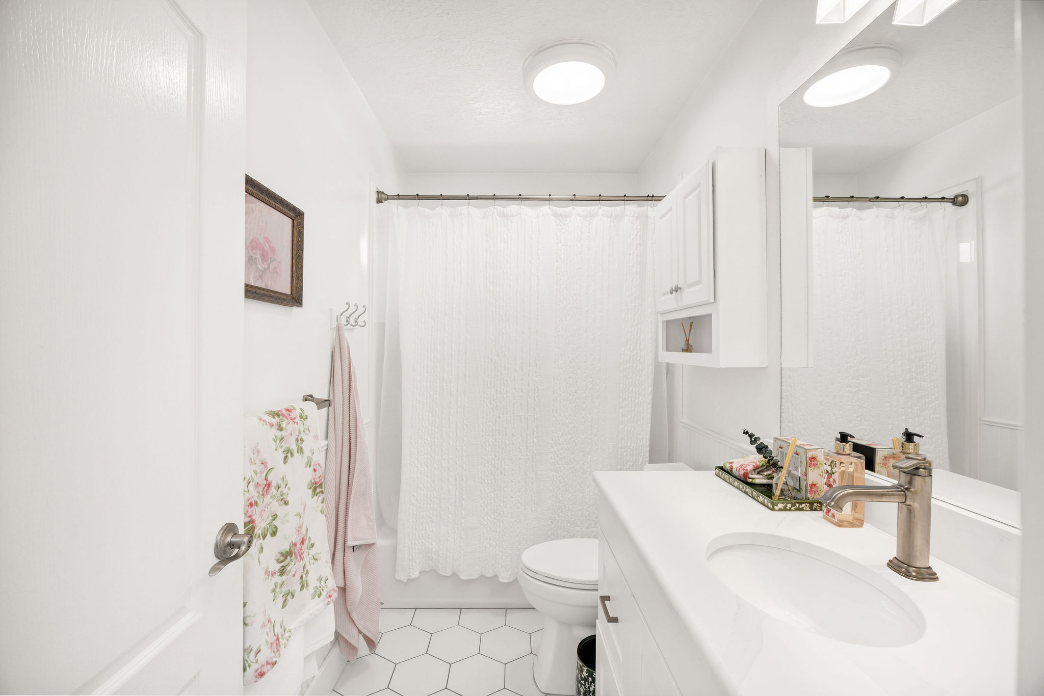 Bathroom featuring a white vanity with an integrated sink, brushed nickel faucet, and a large wall mirror