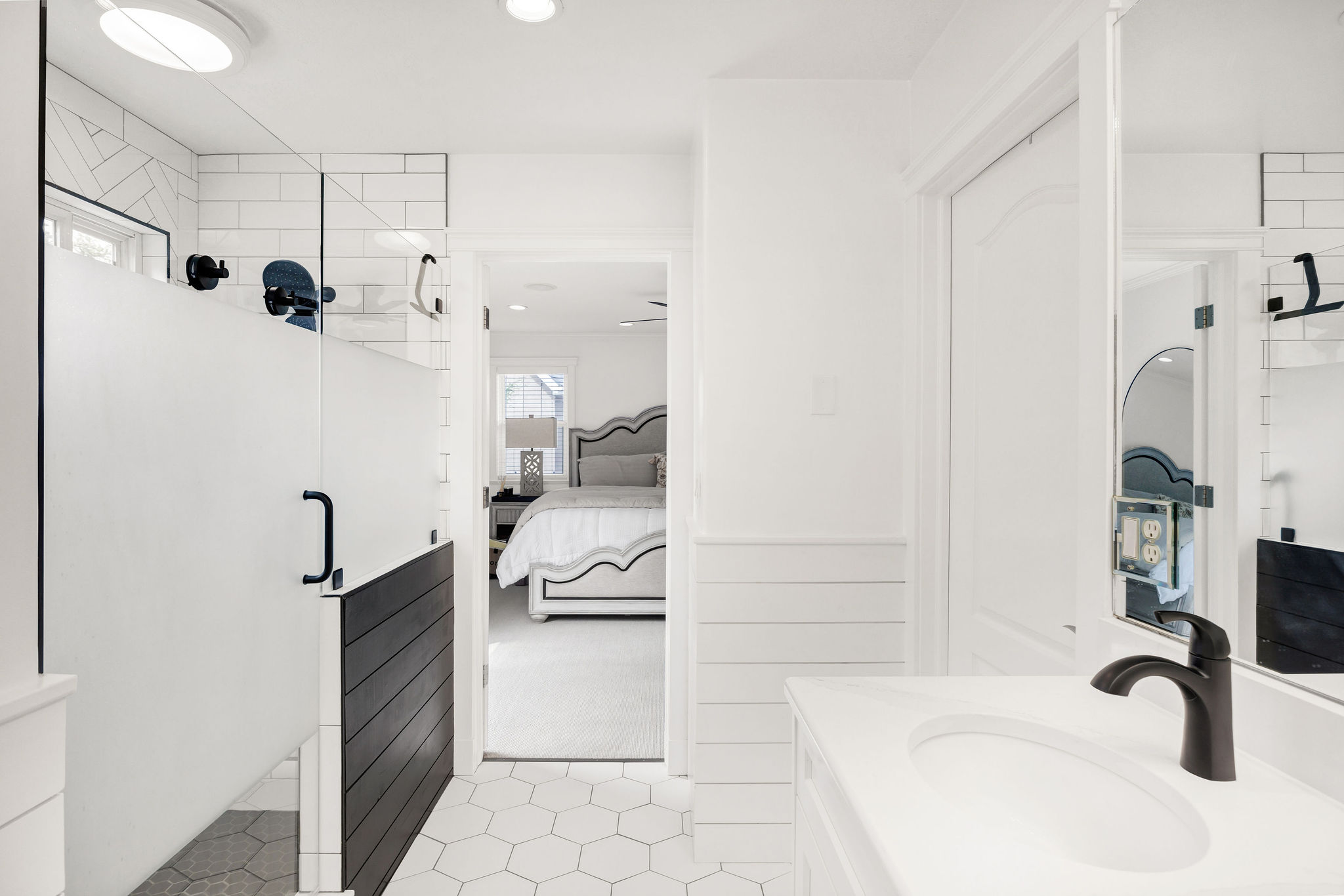 Bathroom featuring a glass-enclosed shower with frosted panel, hexagonal floor tiling, a white vanity with integrated sink, and a matte black faucet