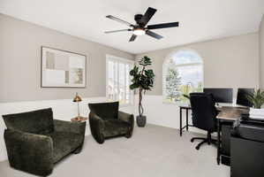 Carpeted room featuring a ceiling fan with integrated lighting, white wainscoting, and an arched window