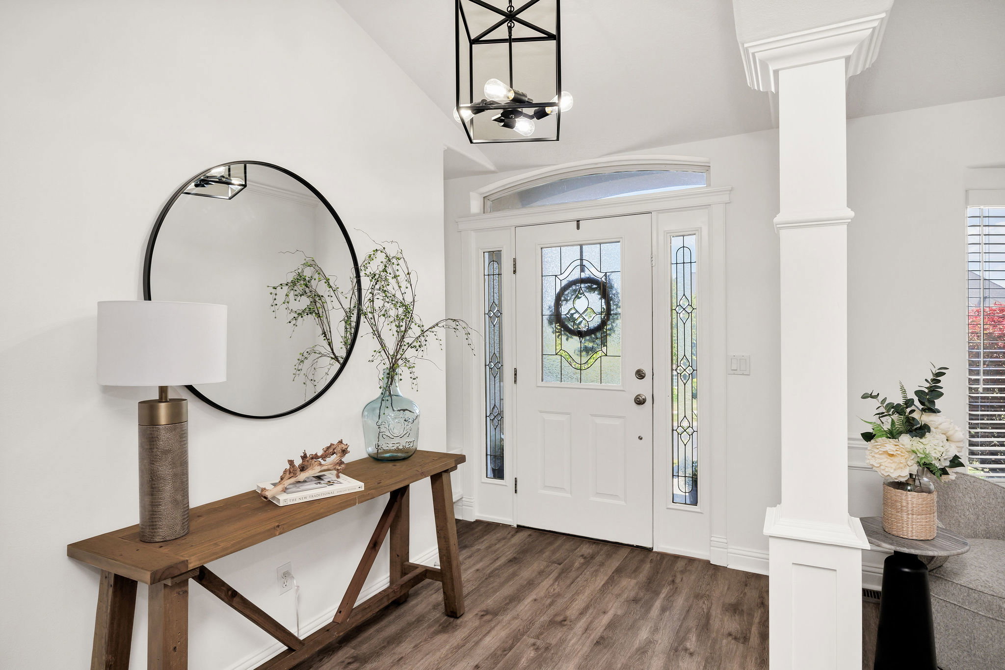 Entryway featuring wood-finish flooring, a white paneled door with leaded glass, an arched transom, and decorative sidelights
