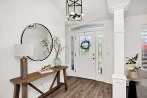Entryway featuring wood-finish flooring, a white paneled door with leaded glass, an arched transom, and decorative sidelights