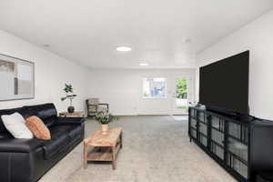 Spacious living area featuring light-colored carpeting, multiple recessed ceiling lights, and white painted walls