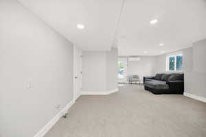 Spacious room featuring light gray walls, recessed lighting, gray carpet flooring, a white trim package, and a white door with dark hardware