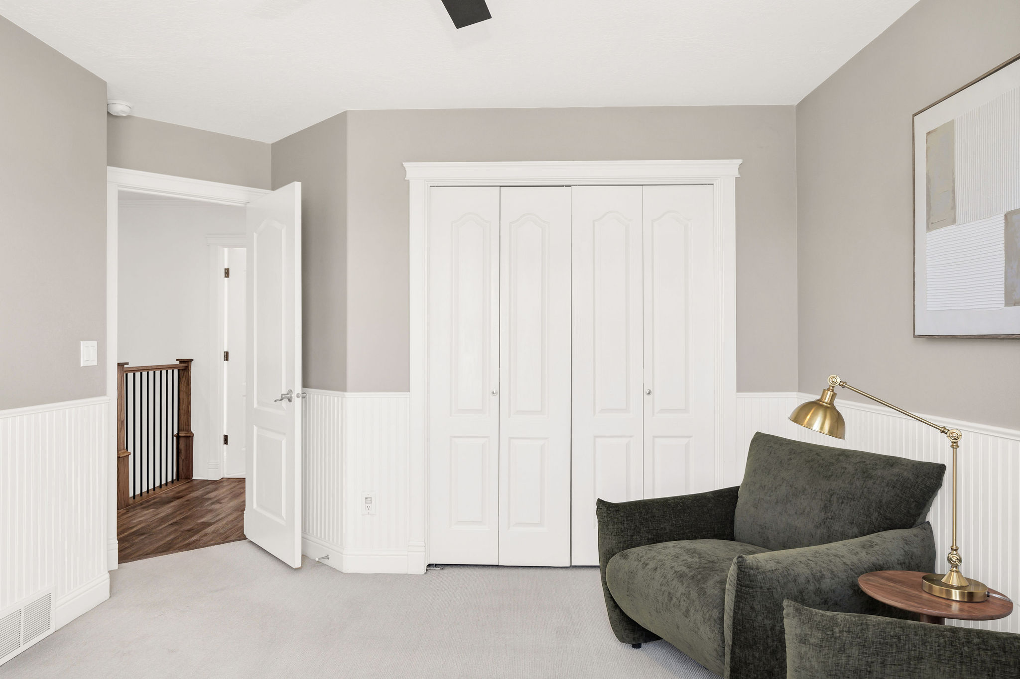 Room featuring light gray walls, white wainscoting, and a light-colored carpet