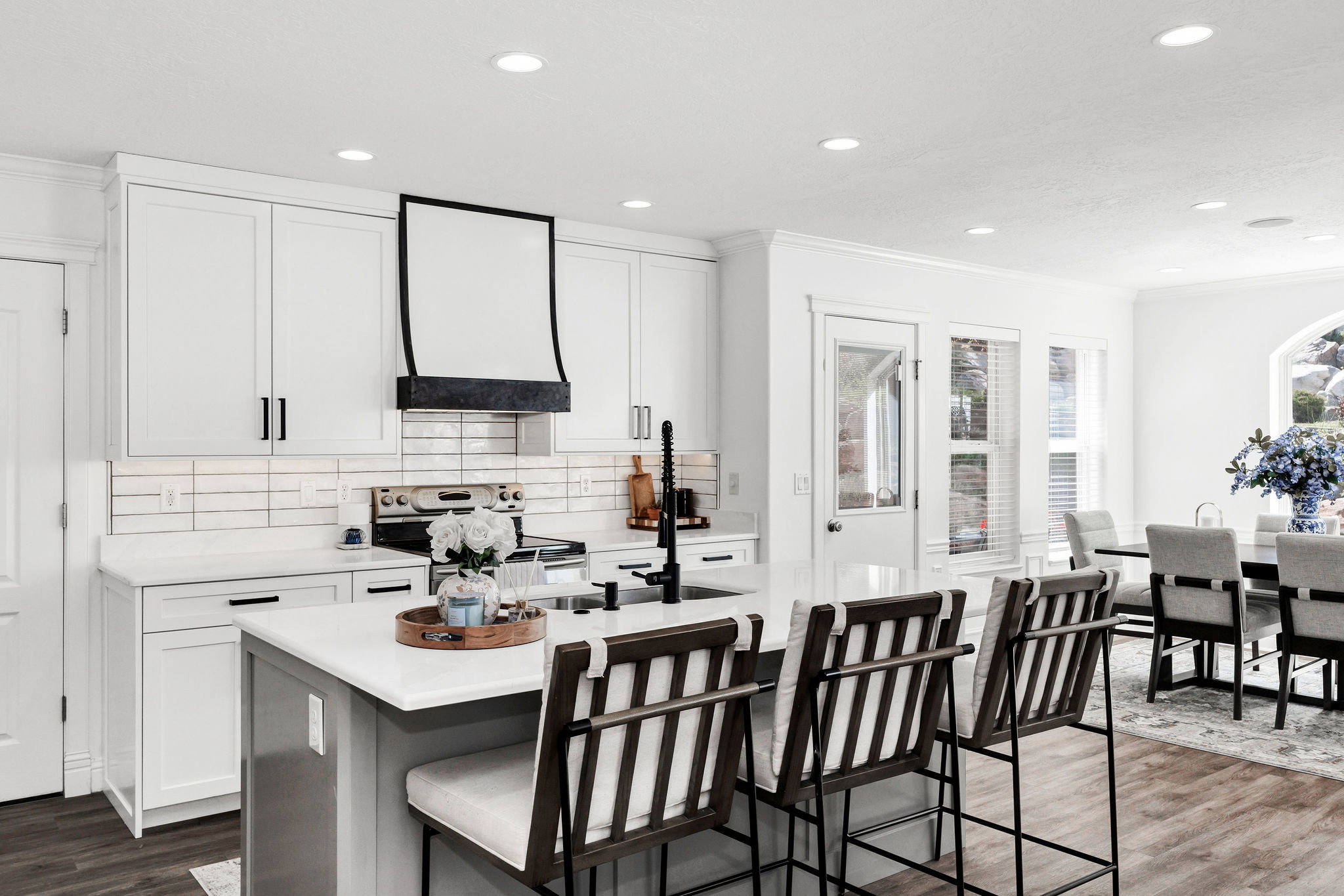 Kitchen featuring white shaker cabinetry, an island with seating, dark wood-finish flooring, recessed lighting, and a white subway tile backsplash