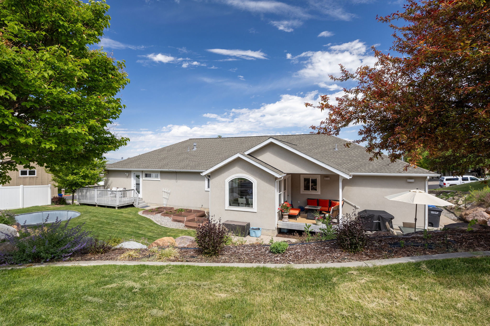 Expansive backyard featuring a manicured lawn, a large wood deck, and an additional covered patio area